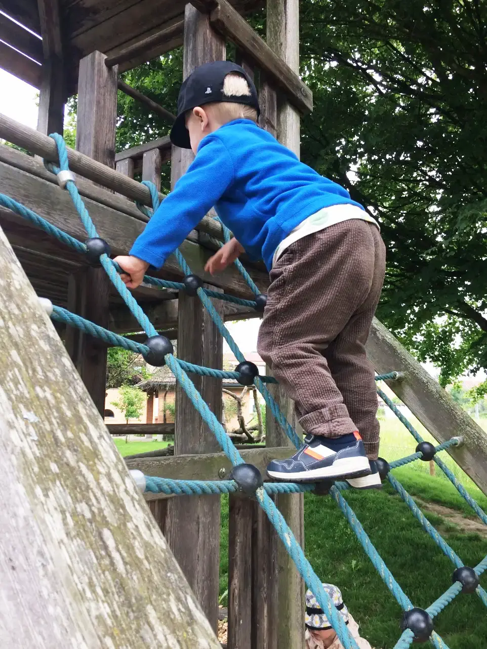 Kind klettert an einem Baumstamm als Ausdruck für Bewegung und motorische Entwicklung
