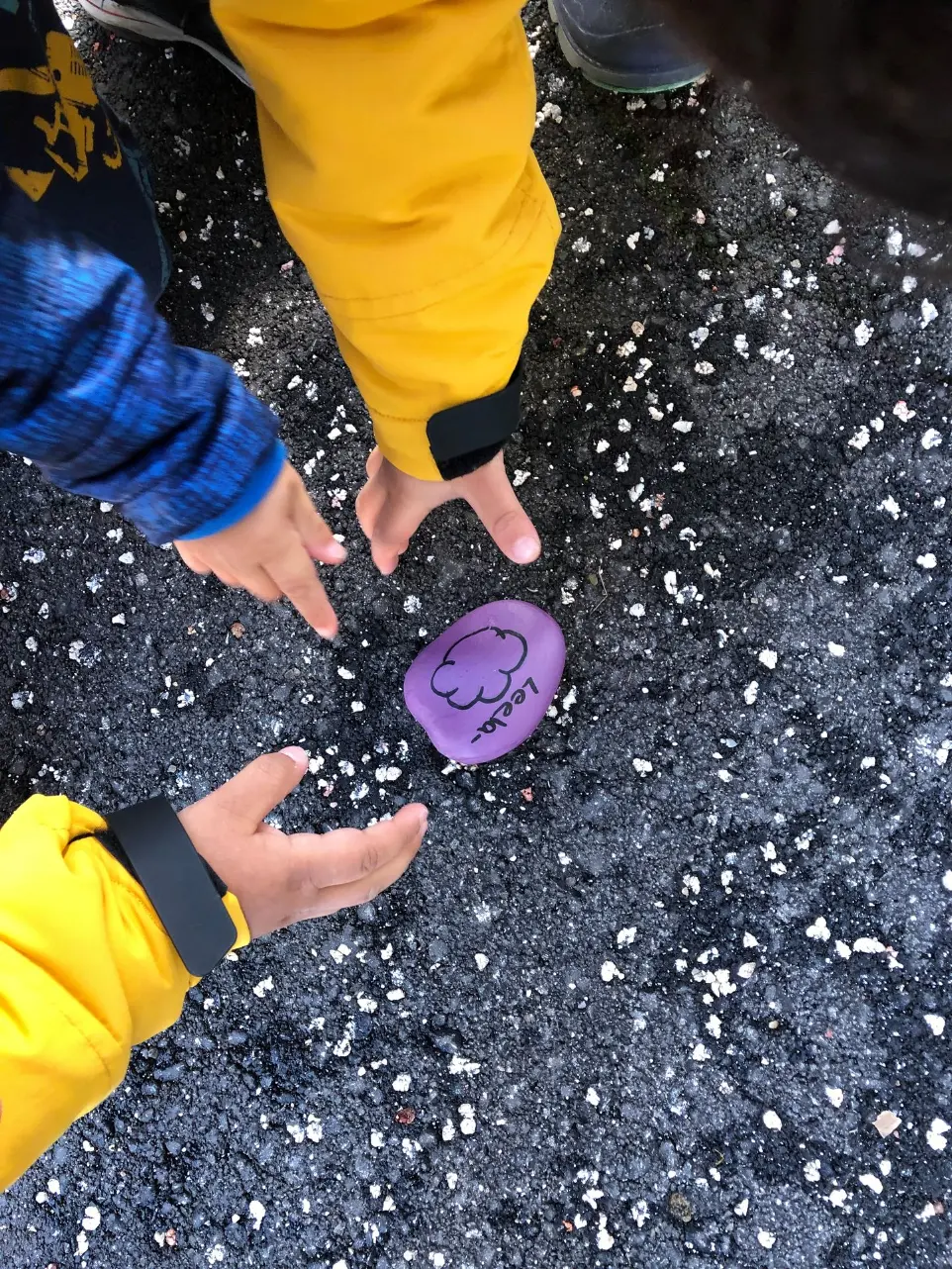 Kinderhände greifen einen Stein mit Wolkenmotiv als kreatives Element des Kita-Alltags